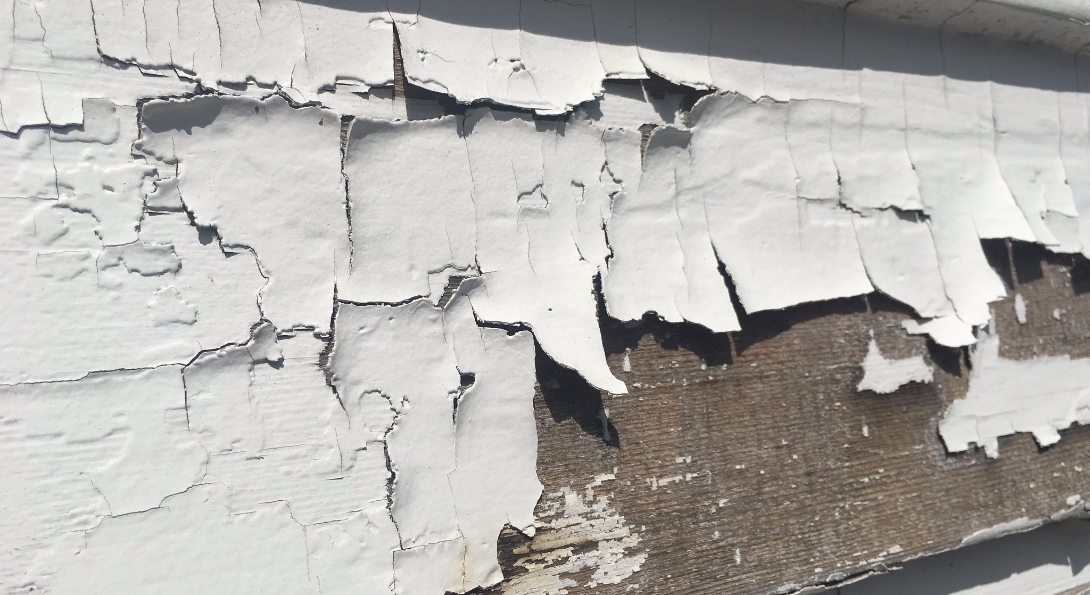 Paint peels away from a wall board.