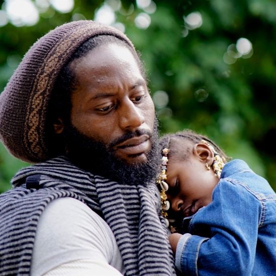 A Black father holds his sleeping daughter.