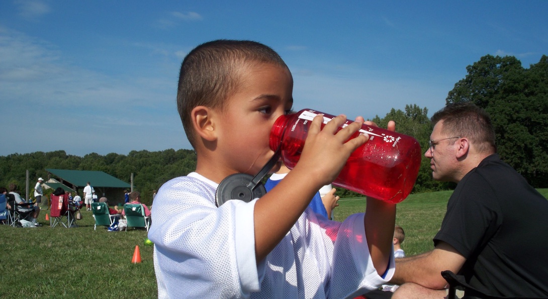 A child drinks water from a Nalgene bottle.