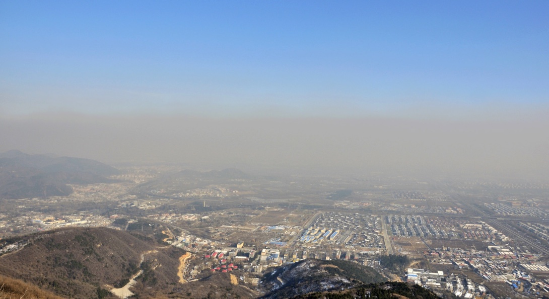 A view from a mountain of smoggy air covering an urban valley.