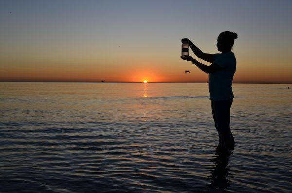 A person holds up a bottle of water from Lake Michigan that will be submitted for testing for chemicals and bacteria.