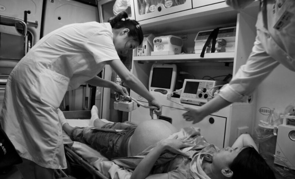 A prenatal nurse conducts an ultrasound on the belly of a pregnant woman.