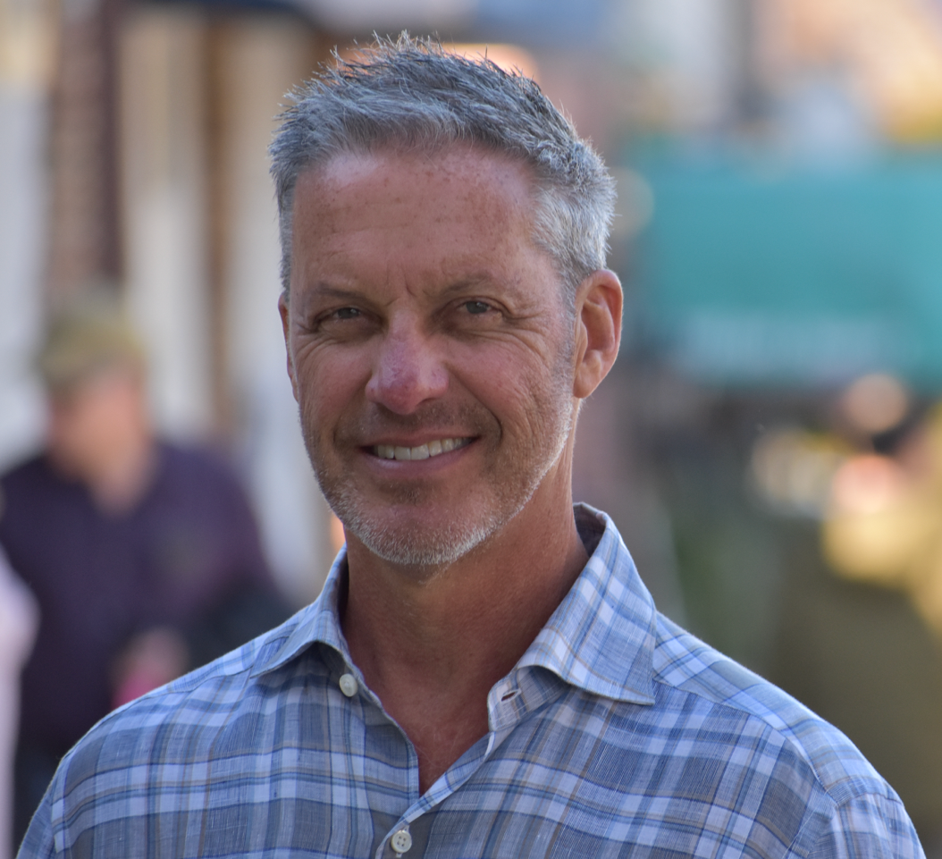 Dr. Bruce Bekkar, PhD wearing a plaid shirt smiling for a picture.